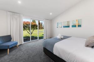 a bedroom with a bed and a chair and a window at Above Par Golf Course Villa with Hot Tub 4bd3bth in Rotorua