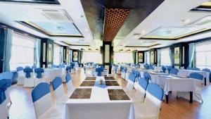 a banquet hall with white tables and blue chairs at Sea Pearl Cat Ba Hotel in Cat Ba