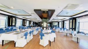 Sea Pearl Cat Ba Hotel في كات با: عربة طعام القطار بالطاولات البيضاء والكراسي الزرقاء