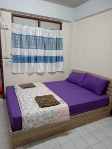 a bedroom with a bed with purple sheets and a window at Natcha Place TU Rangsit in Ban Bang Khan