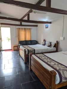 a room with three beds and a window at Guddadamane Homestay in Chikmagalūr