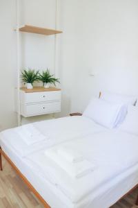 a white bed in a bedroom with two potted plants at Lechner4 Residence in Szeged