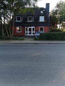 a red house with a car parked in front of it at Hornbrooker Hostel in Dersau