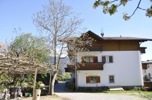 une maison blanche avec un arbre en face dans l'établissement Garni Kofler, à Tirolo