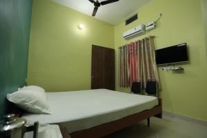 Hotel Virasat Retreat في باتنا: غرفة نوم بسرير وتلفزيون بشاشة مسطحة