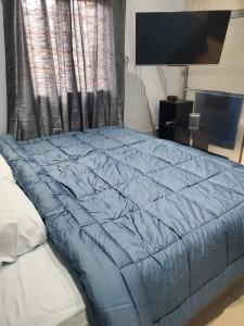 un edredón azul en una cama en un dormitorio en Preferred Place, en Trincity 