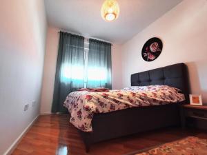 a bedroom with a bed with a comforter and a window at Apartman Angel in Osijek