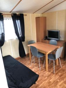 een kamer met een tafel en stoelen en een televisie bij Mobil-home 5 personnes proche de la plage in Berck-sur-Mer