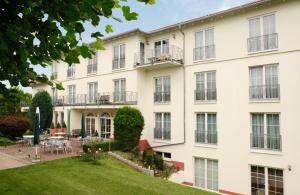 an exterior view of a white building with a yard at Hotel Zielonka in Hochheim am Main