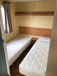 two beds in a small room with a window at Mobil-home 5 personnes proche de la plage in Berck-sur-Mer