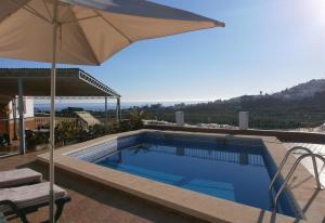 a swimming pool with an umbrella and a table and chairs at El Puntal de Nieves in Nerja