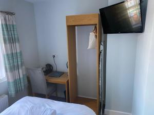 a bedroom with a desk with a television and a bed at Queen Street Tap in Deal