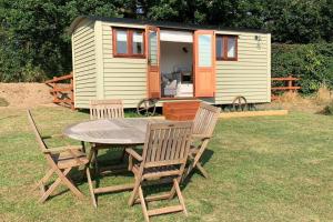 een tafel en stoelen voor een tiny house bij Idyllic Shepherds Hut, Bylaugh, in private wildflower meadow in Swanton Morley