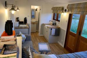 a living room with a couch and a kitchen at Idyllic Shepherds Hut, Bylaugh, in private wildflower meadow in Swanton Morley