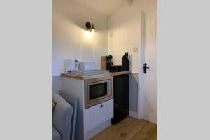 a kitchen with a sink and a microwave in a room at Idyllic Shepherds Hut, Bylaugh, in private wildflower meadow in Swanton Morley