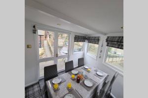 ein Esszimmer mit einem Tisch und zwei Fenstern in der Unterkunft North Lea charming cottage in stunning Staithes in Staithes