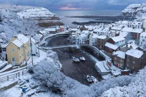 a town covered in snow with houses and a harbor at North Lea charming cottage in stunning Staithes in Staithes