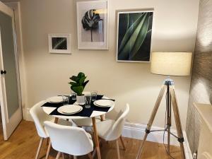 a dining room with a black table and white chairs at The Portside Apartment in Greenock