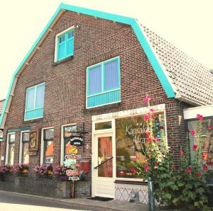 a brown brick building with blue windows and flowers at Valhalla in Egmond-Binnen