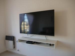 een flatscreen-tv zittend op een witte muur bij Andoli 2 in Santa Rosa