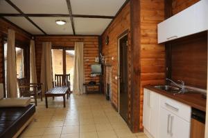 a kitchen with wooden walls and a living room at Krutiki Resort in Turgoyak