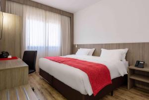 a bedroom with a large bed with a red blanket at Ramada Encore by Wyndham São Paulo Osasco in Osasco