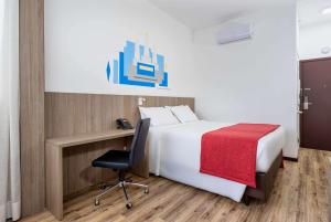 a bedroom with a bed and a desk and a chair at Ramada Encore by Wyndham São Paulo Osasco in Osasco