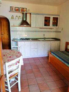 cocina con armarios blancos, mesa y fregadero en Villa Perla, en Capoliveri