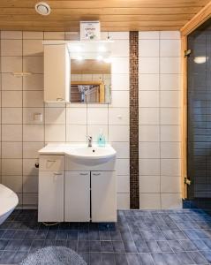 a bathroom with a white sink and a shower at Mäntyruka Cottages in Ruka