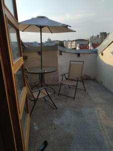 a table and chairs and an umbrella on a balcony at Garsoniera 2 lângă plaja in Constanţa