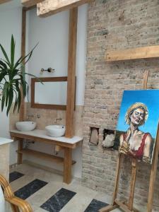 a bathroom with a painting of a woman on a brick wall at Garsoniera 2 lângă plaja in Constanţa