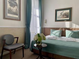 1 dormitorio con 1 cama, 1 silla y 1 jarrón de flores en Отель «БИАНКИ», en Velikiy Novgorod