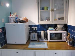 a kitchen counter with a microwave and a refrigerator at The Creamery in Liskeard