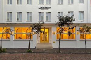 un edificio blanco con luces amarillas en las ventanas en Logierhaus Austernfischer, en Norderney