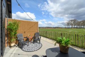 a patio with two chairs and a table and a fence at Onder de Molen in Garderen