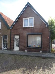 a brick house with a white door and a window at Kustverhuur, Breskens, Nijverheidstraat 11 in Breskens