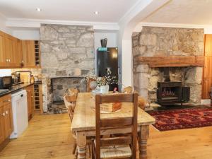 een keuken met een houten tafel en een stenen open haard bij Tan Y Bryn in Beaumaris