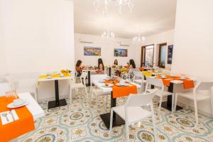 a dining room with white tables and orange accents at Panariello Palace in Agerola