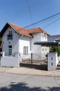 a white house with a gate on a street at Sweet Home in Valjevo