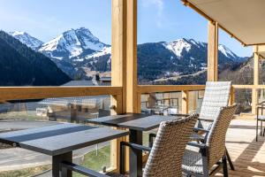 uma mesa e cadeiras numa varanda com montanhas em FranceComfort - AlpChalets Portes du Soleil em Abondance