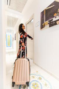 Uma mulher num quarto com uma mala. em Panariello Palace em Agerola