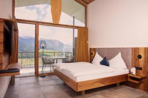 een slaapkamer met een bed en een groot raam bij Berghotel Plagött in San Valentino alla Muta