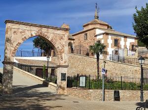 un bâtiment avec une arche en face d'un bâtiment dans l'établissement San Miguel, à Membrilla
