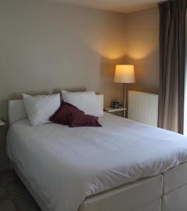 - une chambre avec un grand lit blanc et des oreillers blancs dans l'établissement B Apartment, à Bierbeek