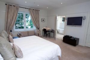 a bedroom with a large white bed and a television at Brucefield Boutique B&B in Arbroath