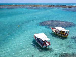 two boats in the water next to a small island at Suites Jangadeiro Maragogi 4 RUA JANGADEIROS 215 in Maragogi +8 photos