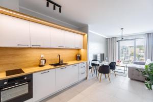 a kitchen with white cabinets and a dining room at Balticus Apartamenty Deluxe Promenada Gwiazd 14 in Międzyzdroje