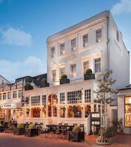 a large white building with tables in front of it at Logierhaus am Denkmal in Norderney