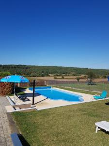 uma piscina com um guarda-sol e duas cadeiras em Hibiskus Appartementhaus em Cserszegtomaj