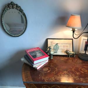 a table with books and a lamp and a mirror at Half Moon House top flat in Hay-on-Wye